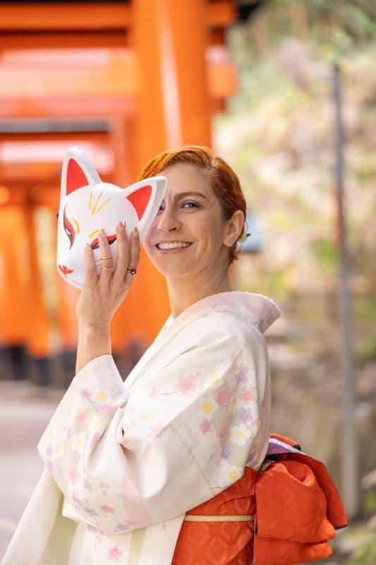 Kalu vestindo um kimono e segurando uma máscara de raposa.