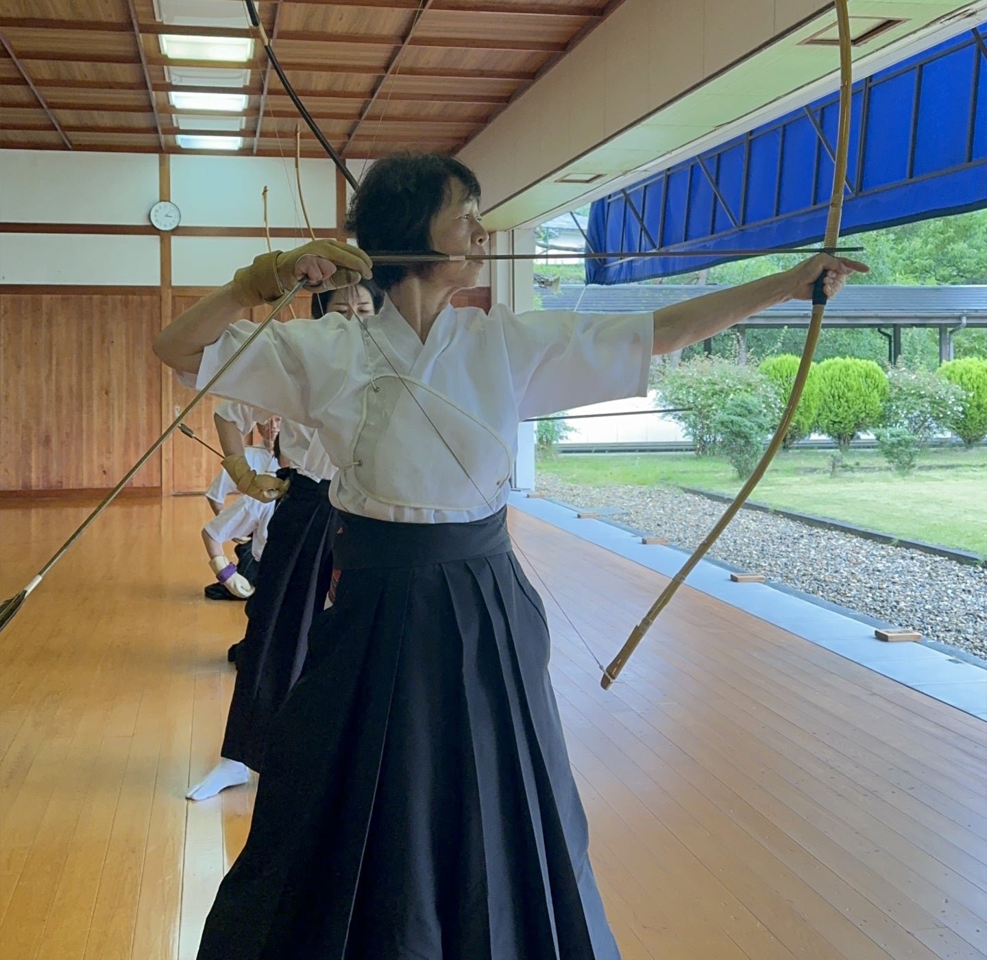 Uma mulher praticando arco e flecha vestindo um uniforme tradicional.