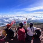 Turistas sentados com bandeiras do Japão no monte Fuji.