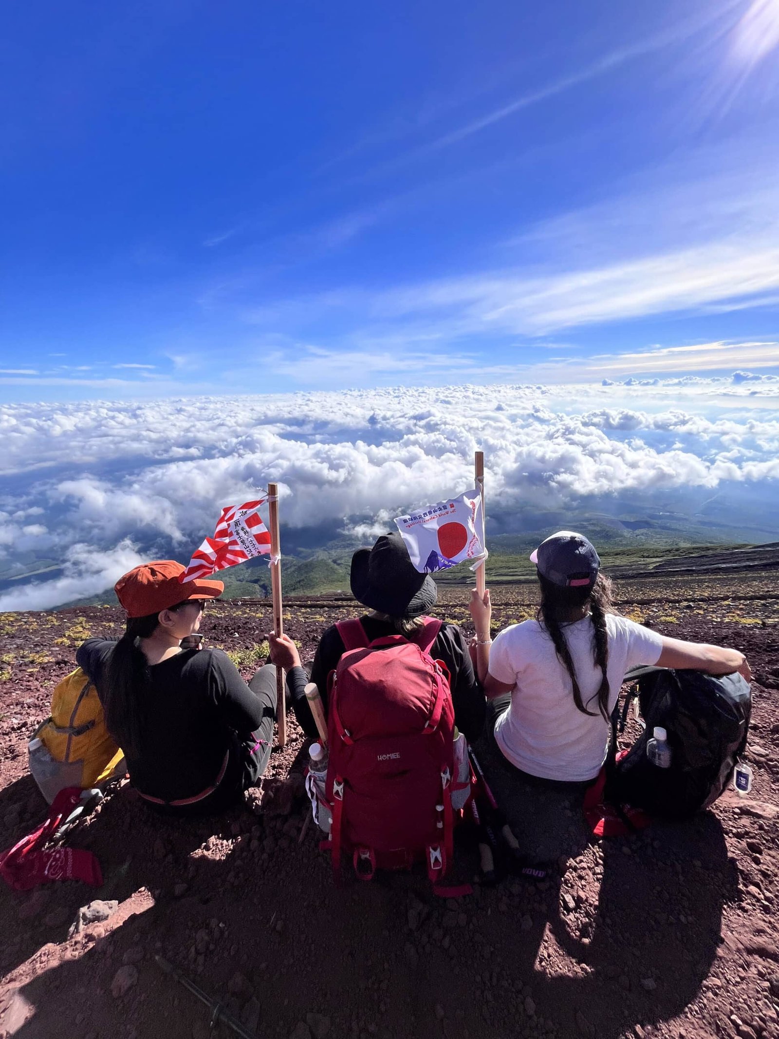 Turistas sentados com bandeiras do Japão no monte Fuji.