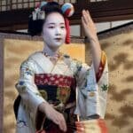 Uma maiko (aprendiz de geiko) posando para a foto como se estivesse dançando.