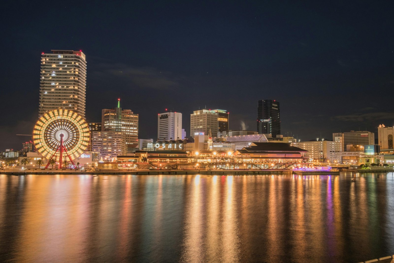 Os prédios de Kobes visto da Baia de Osaka, com suas luzes refletindo na água.
