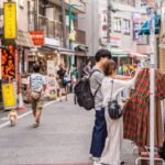 Um casal olhando roupas expostas na calçada, em Shimokitazawa.