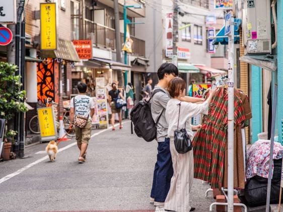 Um casal olhando roupas expostas na calçada, em Shimokitazawa.