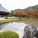 O pavilhão do Tenryu-ji ao lado de seu belo lago, com pessoas tirando foto e cercado de árvores.
